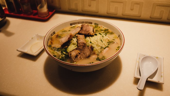 A bowl of ramen with cabbage, pork and noodles as the main dishes