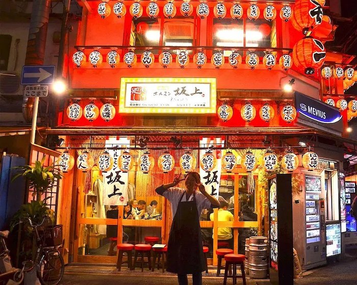 An izakaya in Osaka, with the proprietor standing outstide, at night