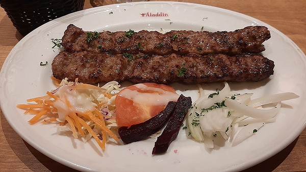 Grilled kebabs with side salad on a white plate at Aladdin restaurant