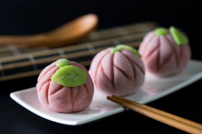 Three pink wagashi with chopsticks