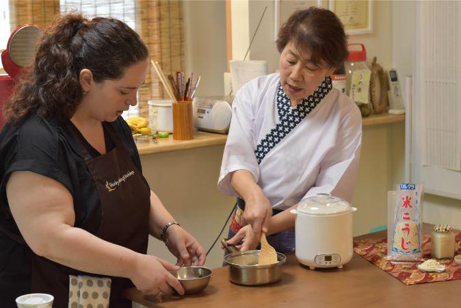 A koji cooking class in Japan, with a host showing a guest what to do.