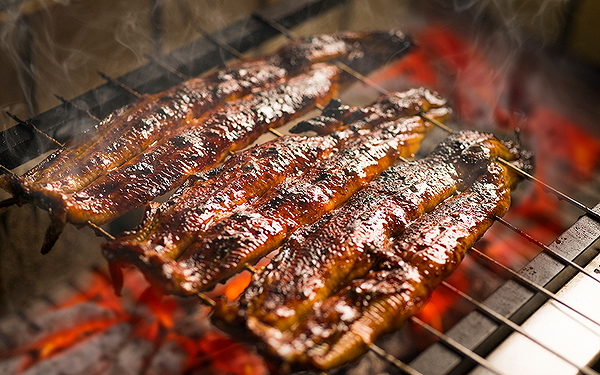 Grilled eel sizzling on a barbecue with a smoky glaze