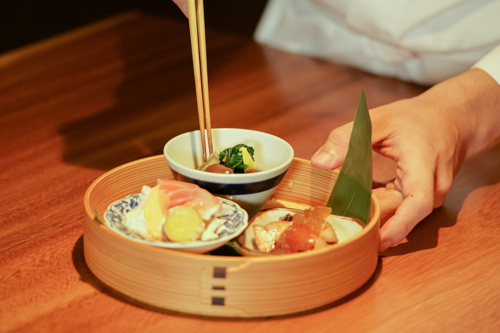 Gourmet course menu with sushi and greens served in elegant dishes