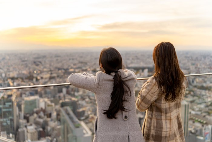 Two women look out over a Tokyo rooftop terrace