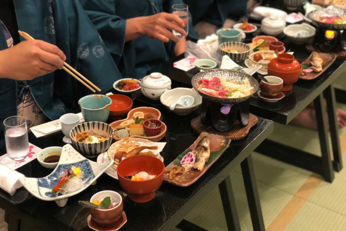 People eating a traditional Japanese meal in a tatami room, on low, small tables