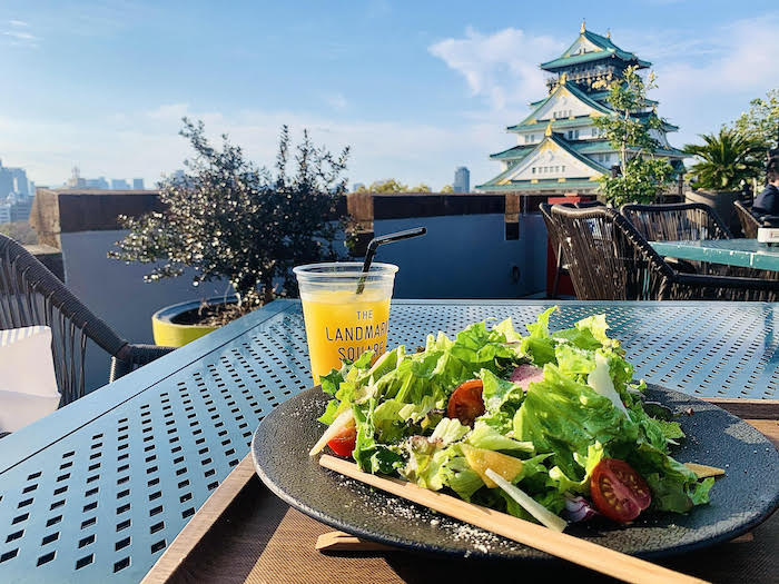 View of Osaka Castle, foregrounded by a salad and juice at Landmark Square Cafe Osaka