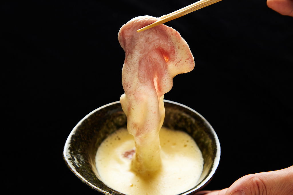 A slice of wagyu beef at Kitashinchi Shabushabu Kiraku, dipped in a broth and ready to be cooked.