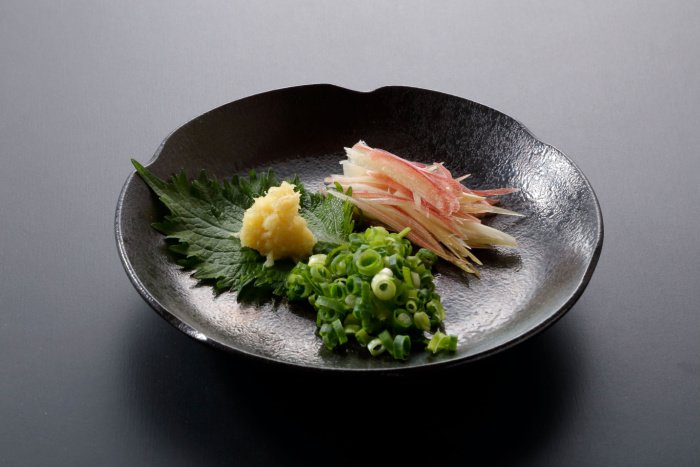 Japanese shiso, ginger, myoga and spring onion on a small black plate