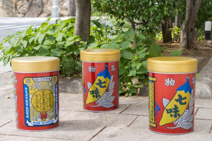 A trio of large shichimi spice cans on a pavement