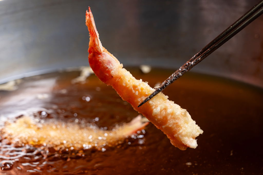 A single ebi tempura being gently fried in bubbling oil at Arakicho Tenpaku (Formerly Kondou).