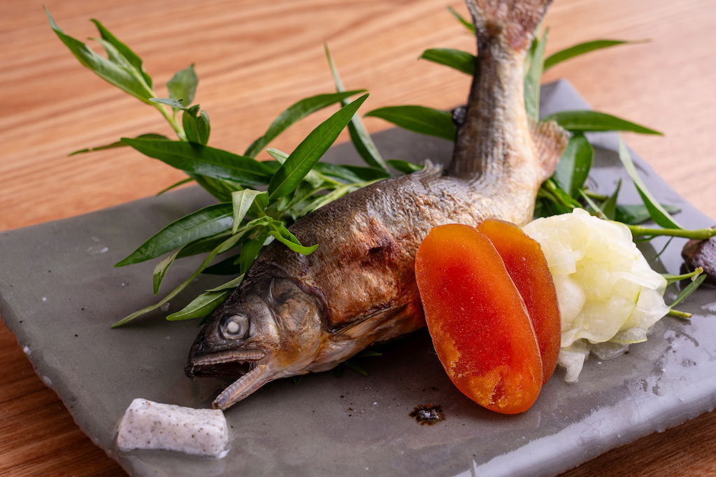Grilled fish with herbs and seasonal accompaniments on a stone plate