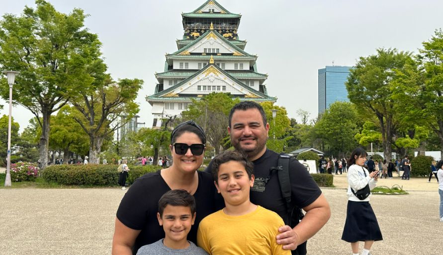 A family smiling in front of the iconic Osaka Castle.