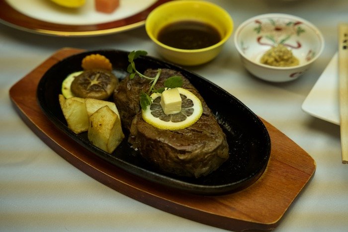 A cut of Kobe beef steak served on an iron plate with potatoes and mushrooms