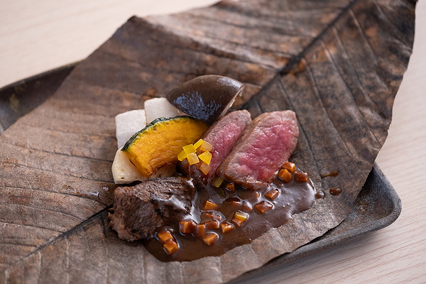 Gourmet beef dish on leaf with sauce and vegetables at a modern restaurant