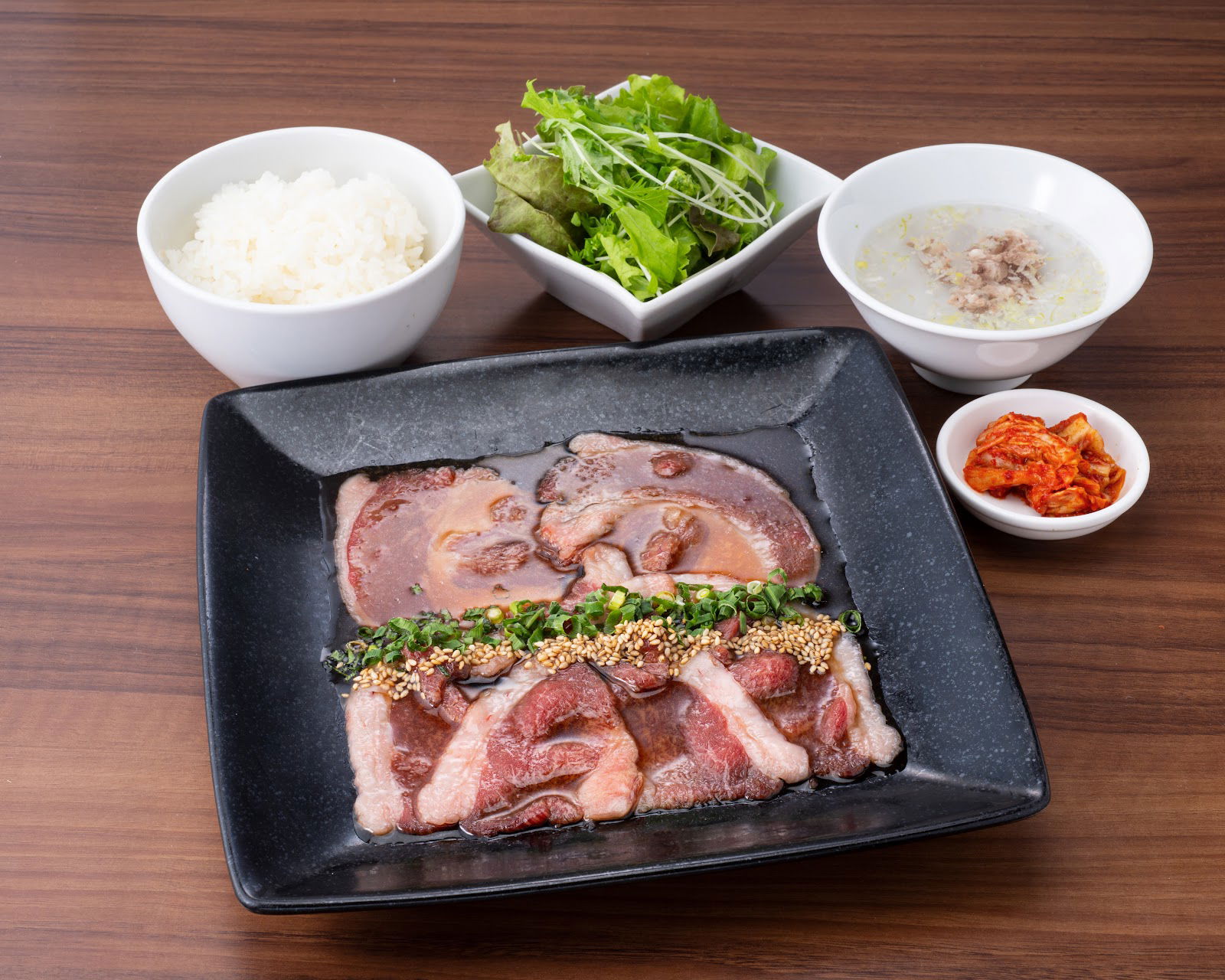 Wagyu beef marinating in a flavorful sauce, served with salad, rice and more.