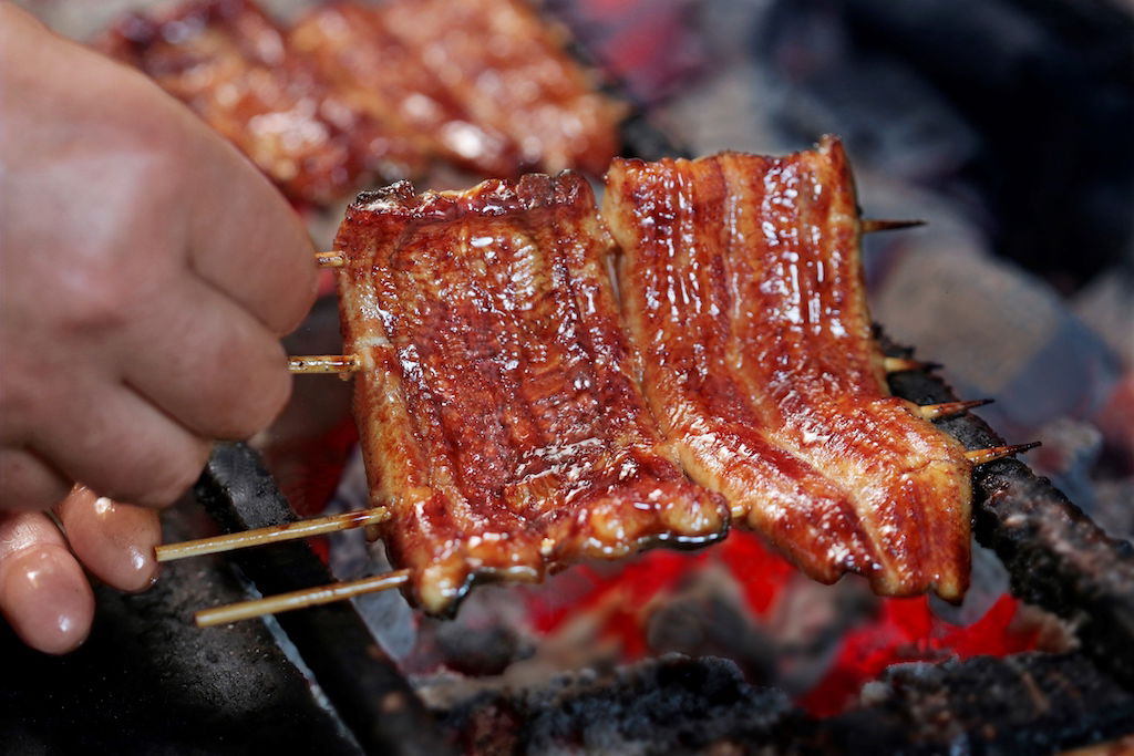 Glossy slices of unagi eel being grilled over charcoal at Unagi Kappo Ooedo.