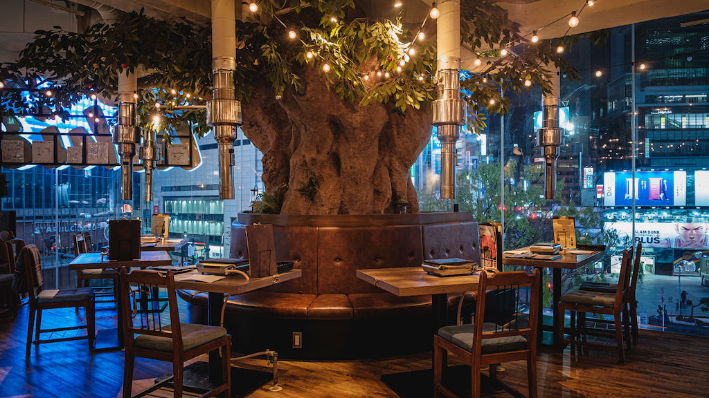 The breathtaking interiors of Shibuya Wagyu Yakiniku USHIHACHI Kiwami, featuring a large, fairy-lit tree at its center.