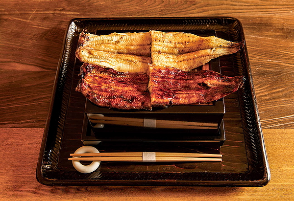 Grilled eel on a traditional Japanese serving tray with chopsticks