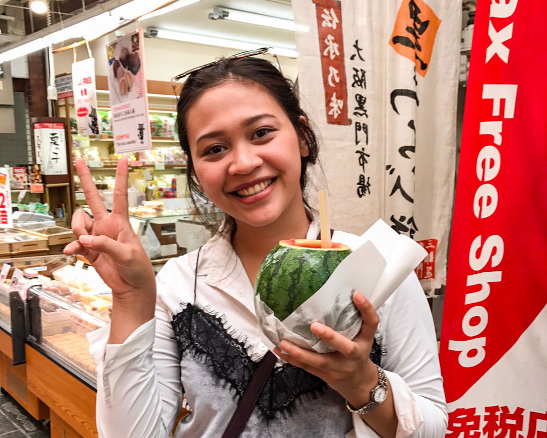 A guest flashing a peace sign while drinking from a watermelon.