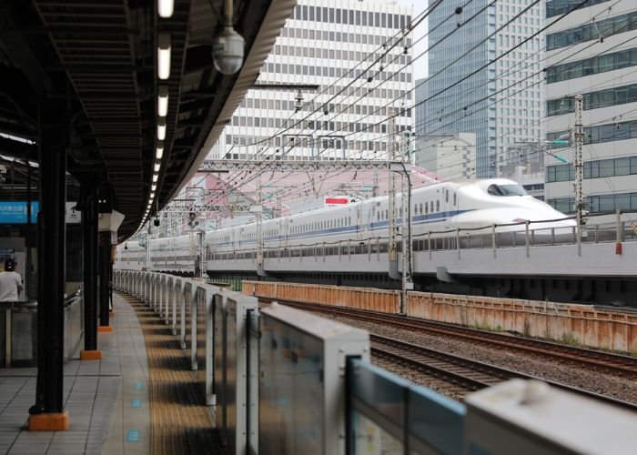 A photo of a Shinkansen train running through Tokyo taken from a train platform.