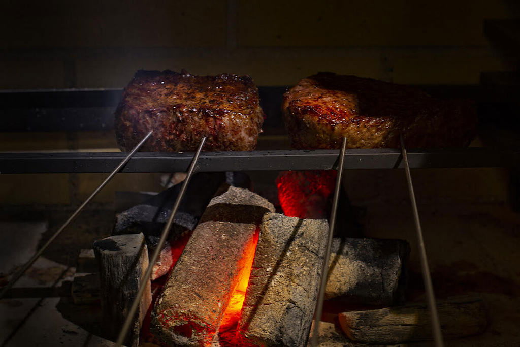 Thick cuts of wagyu beef being cooked in a kiln at Rogama Steak Arcanum.