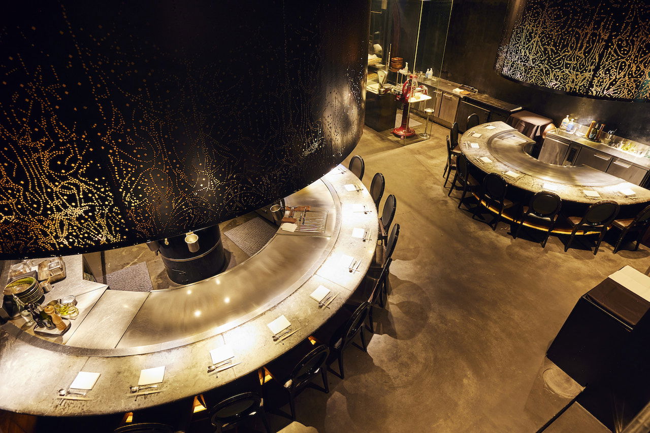 The sleek counter seating of atelier Morimoto XEX, backlit and curving around chefs at their core.