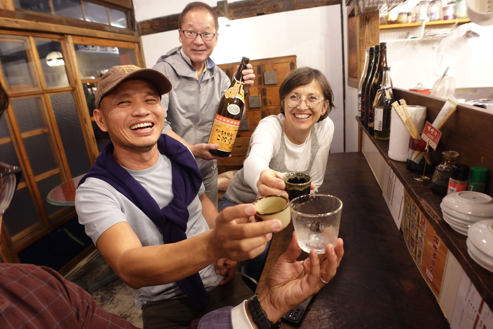 Guests smiling and clinking glasses in this bar-hopping tour in Fukuoka.