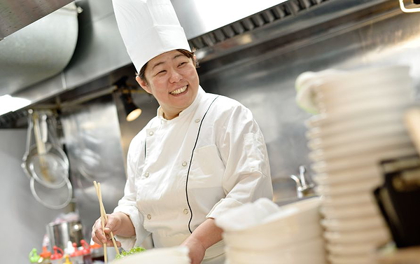 Chef smiling while cooking in a vibrant restaurant kitchen