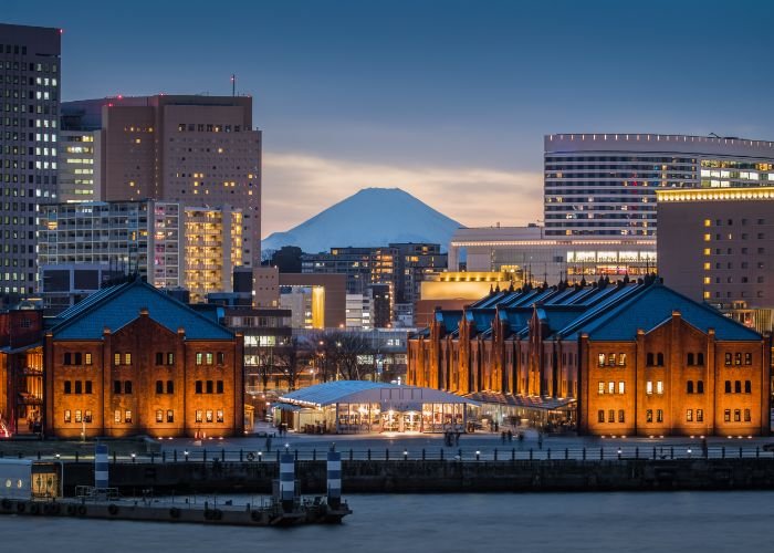 A photo of Yokohama Red Brick Warehouse at dusk with Mount Fuji in the background