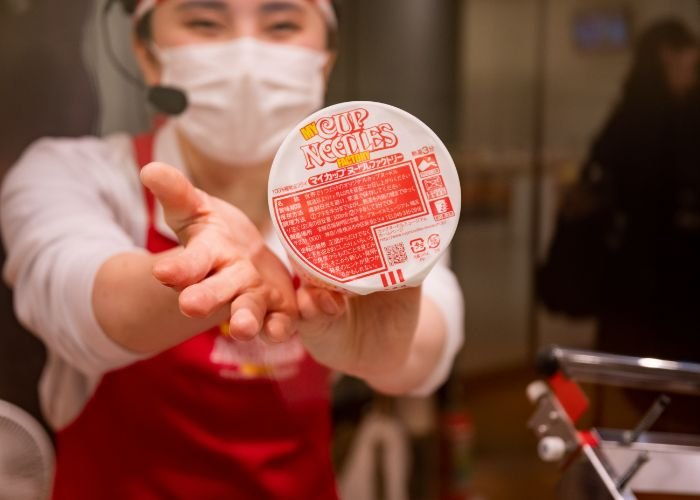 A staff at the Cup Noodles Museum in Yokohama shows a finished custom-order cup noodle pack.