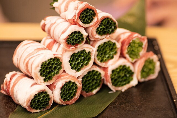 Gourmet rolled appetizers with green filling stacked neatly on a tray