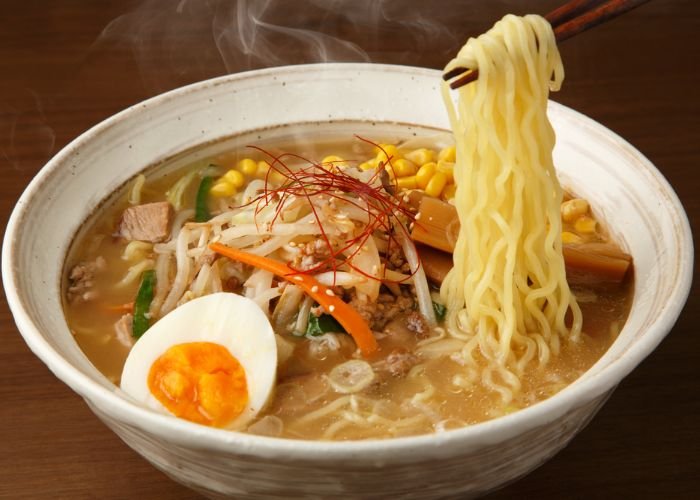A bowl of Sapporo ramen with a boiled egg, corn, noodles and other vegetables