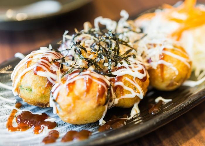 A set of eight takoyaki balls topped with takoyaki sauce, Japanese mayonnaise, seaweed and bonito flakes