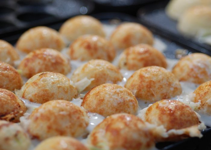 Closeup of homemade takoyaki balls in a takoyaki pan