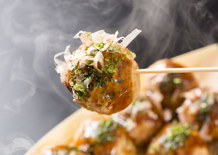 A takoyaki ball with takoyaki sauce topped with seaweed and bonito flakes