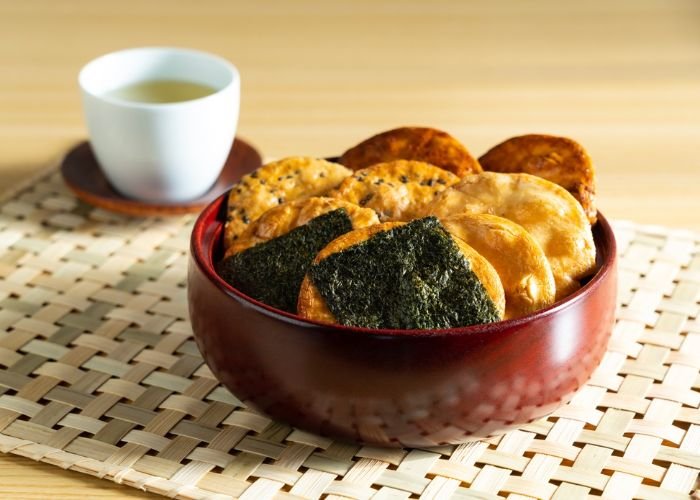 A bowl of senbei (Japanese rice crackers) served with green tea