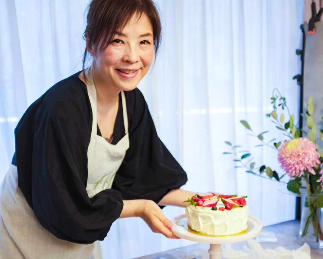 A woman showing off her strawberry shortcake at a cooking class in Tokyo