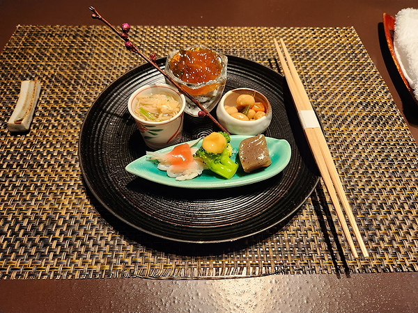 Gourmet Japanese appetizer platter with chopsticks on woven placemat