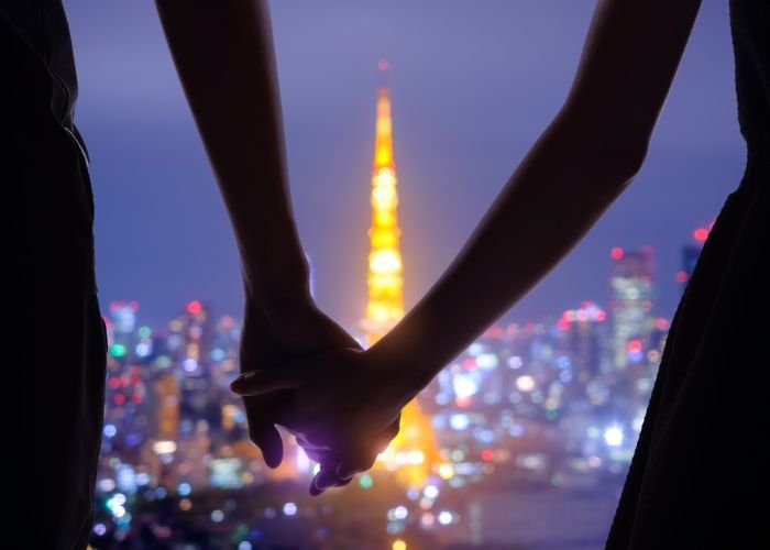 A couple holding hands with a view of Tokyo Tower at night