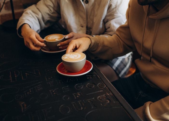 Two people have cappuccinos in a coffee shop