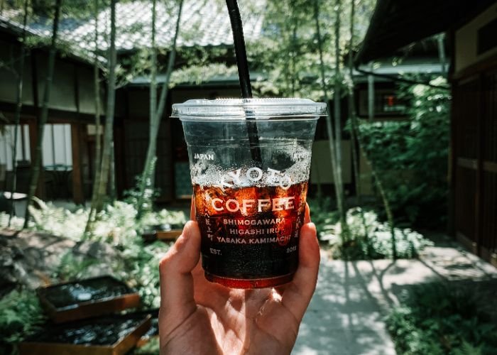 A man holding an iced coffee from a Kyoto coffee shop