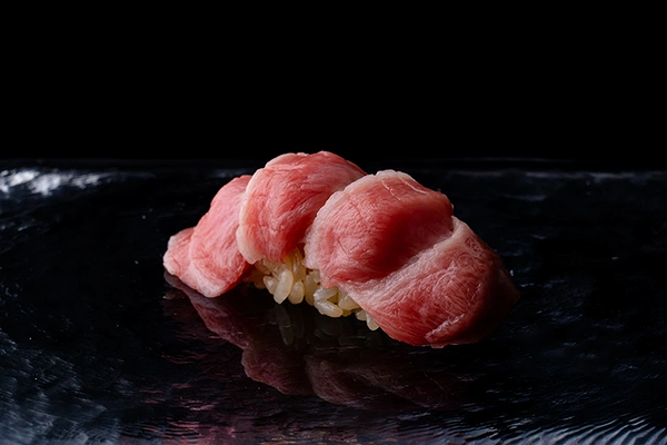 Fresh sushi with pink tuna on black glass surface