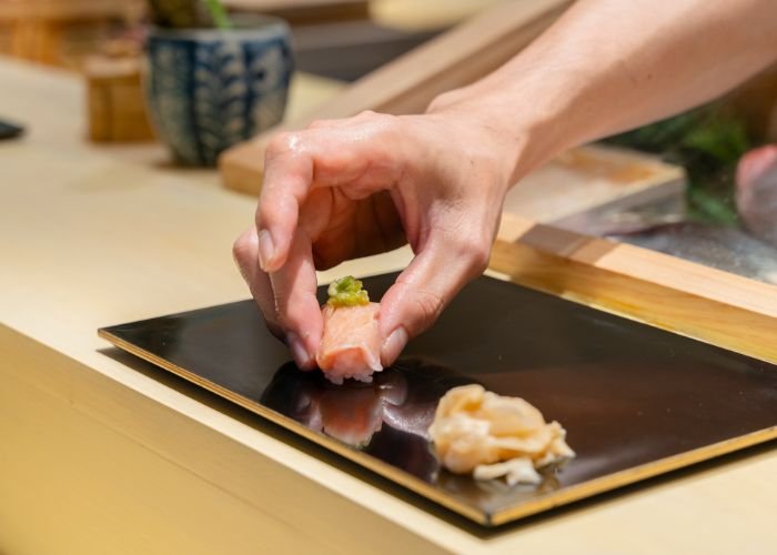 A sushi chef puts down a freshly made nigiri sushi during an omakase sushi course in Japan