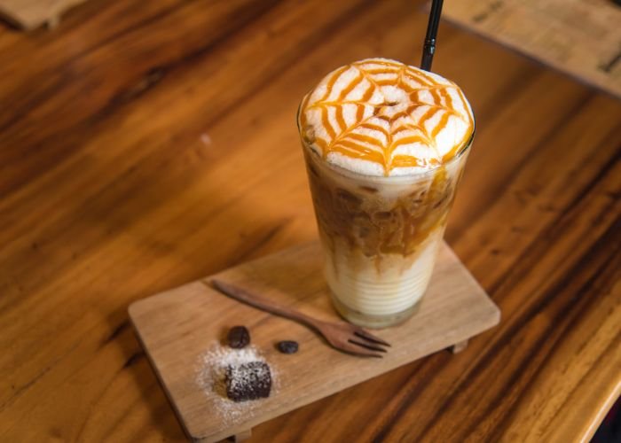 A photo of an iced coffee with a piece of chocolate on the side