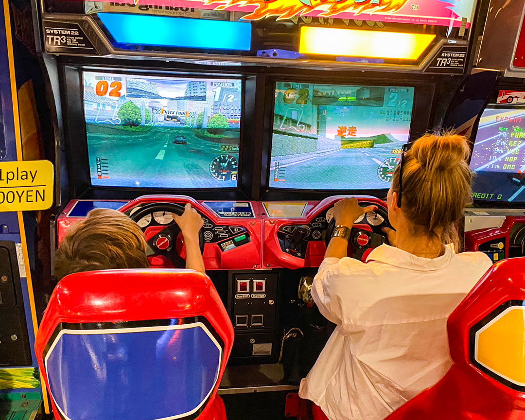 Two kids playing a racing game at an arcade in Akihabara.