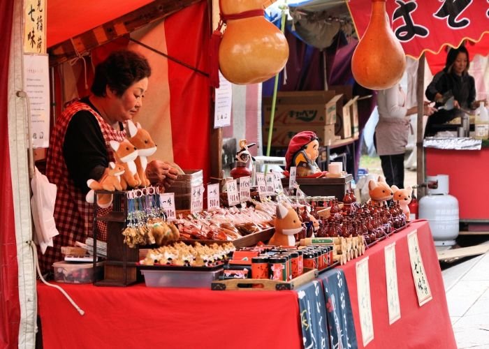 Vendor sells souvenirs at Kitano Tenmangu shrine flea market in Kyoto, Japan