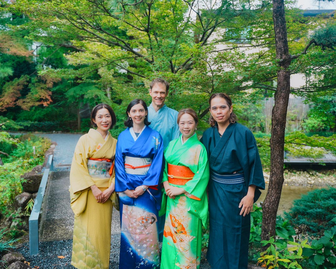 Five guests on this tea ceremony experience in Tokyo, wearing kimono in a natural, leafy setting.