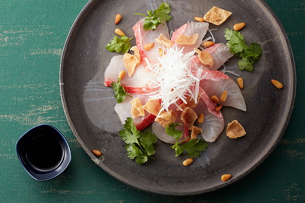 Elegant sashimi platter with cilantro and pine nuts at gourmet restaurant