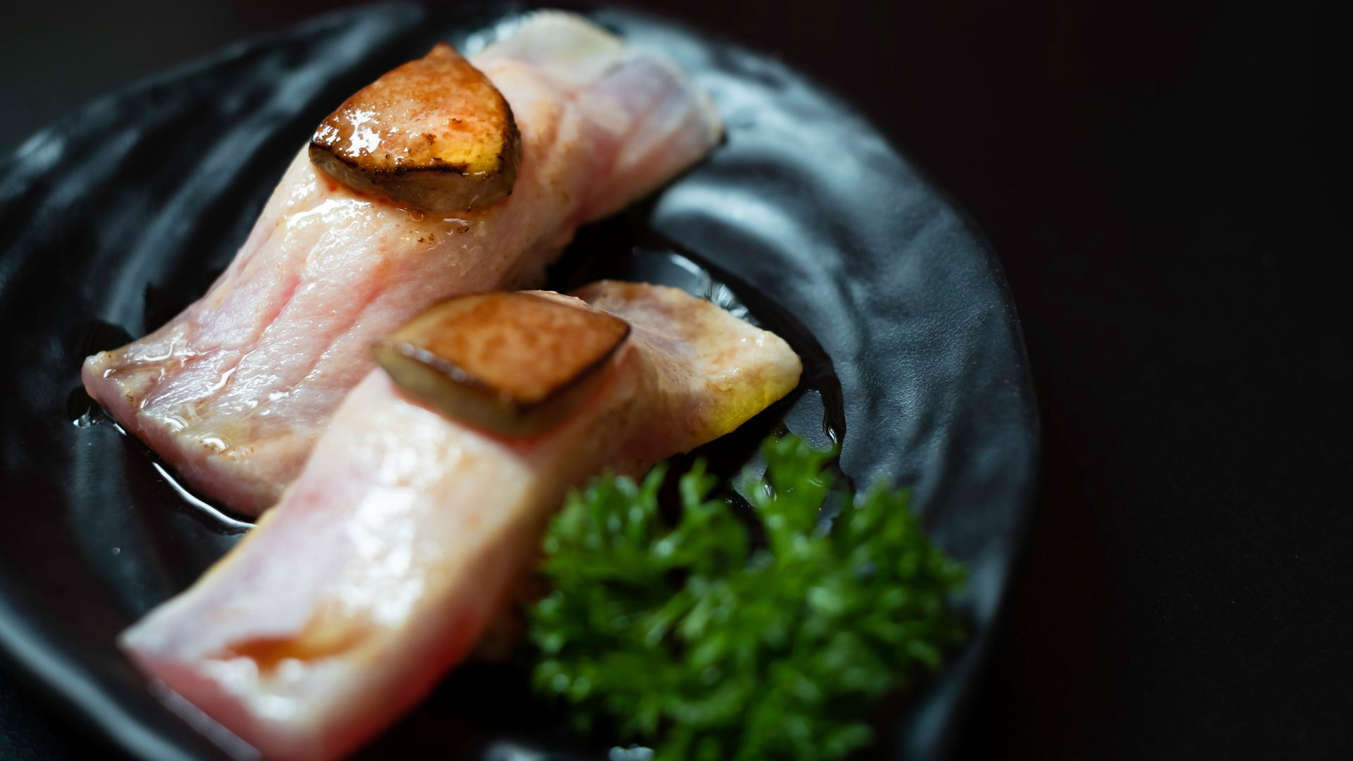 Gourmet fish and foie gras dish with fresh herbs on black plate