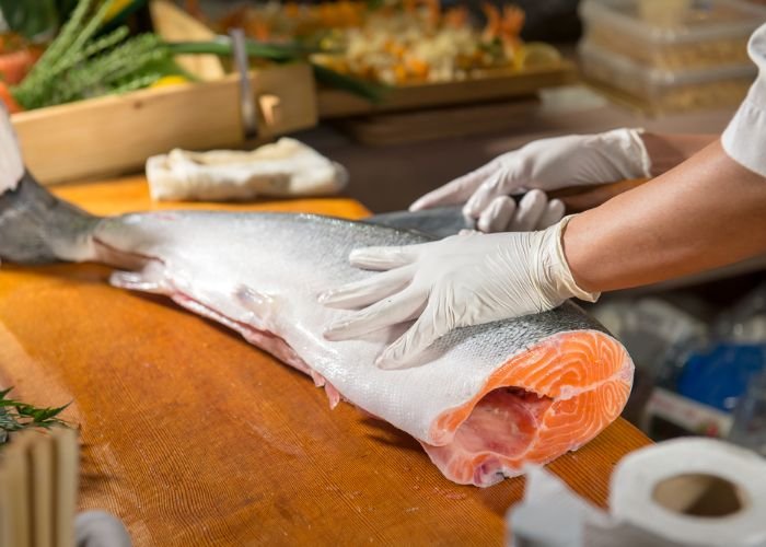 A chef is cutting fresh salmon to make sushi in Japan